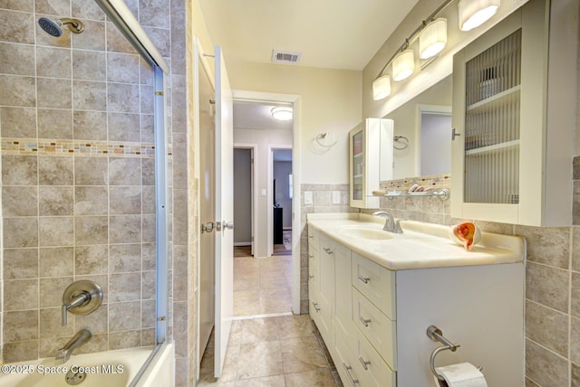 bathroom with vanity, combined bath / shower with glass door, and tile walls