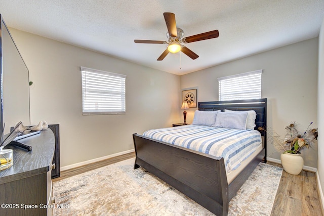 bedroom featuring ceiling fan, light hardwood / wood-style floors, and a textured ceiling