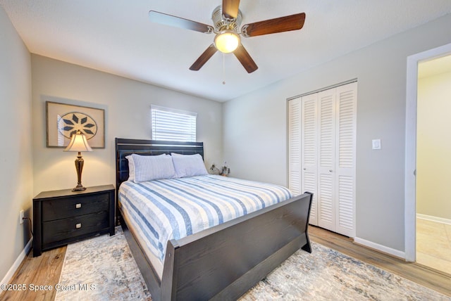 bedroom with light wood-type flooring, ceiling fan, and a closet