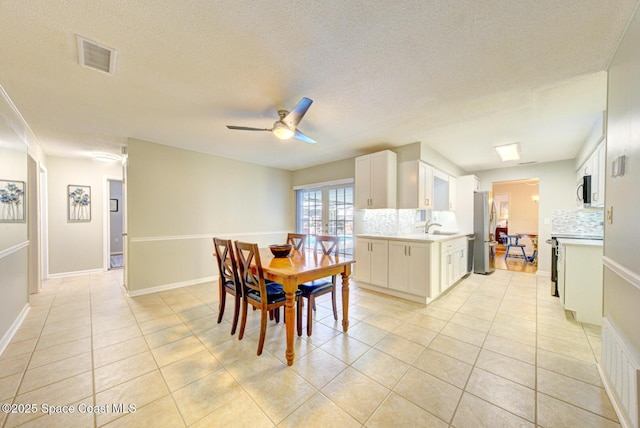 tiled dining space featuring ceiling fan, sink, and a textured ceiling