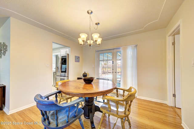 dining room featuring an inviting chandelier, light hardwood / wood-style floors, and french doors