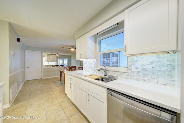 kitchen with sink, light tile patterned floors, stainless steel dishwasher, white cabinets, and backsplash