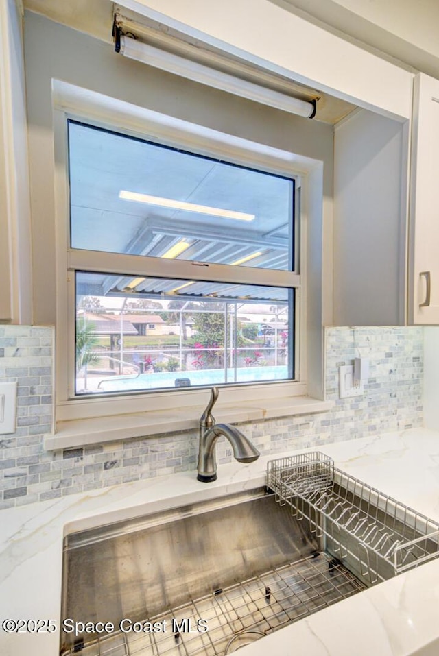 details featuring sink, decorative backsplash, and light stone countertops