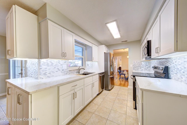 kitchen featuring stainless steel appliances, white cabinetry, sink, and backsplash