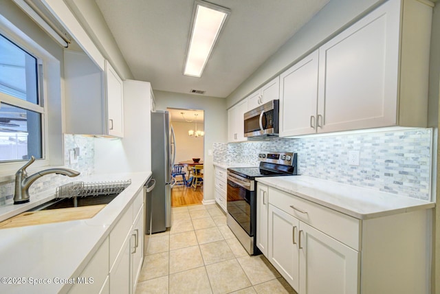 kitchen featuring sink, tasteful backsplash, light tile patterned floors, stainless steel appliances, and white cabinets