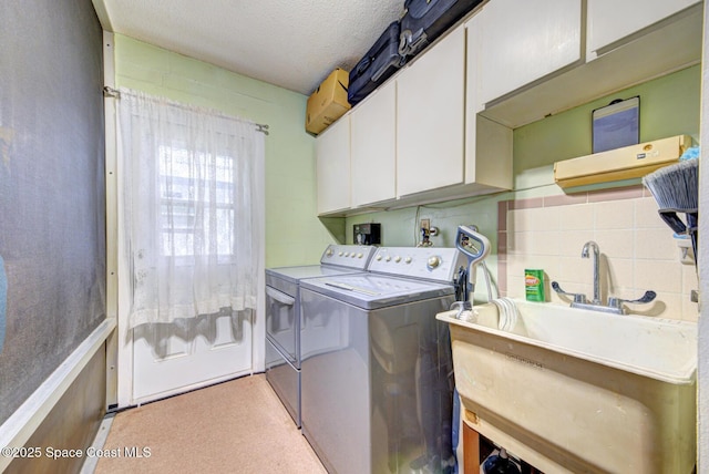 laundry area with cabinets, sink, washer and dryer, and a textured ceiling