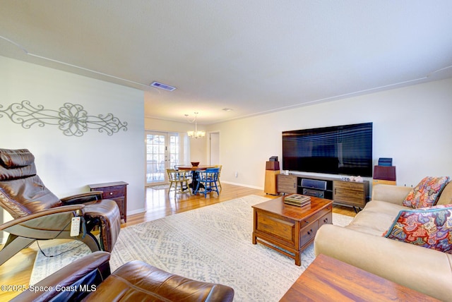 living room with an inviting chandelier and light hardwood / wood-style flooring