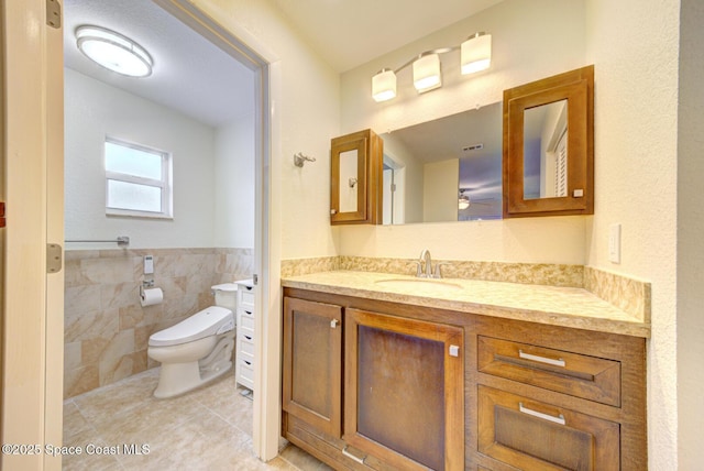 bathroom featuring tile patterned floors, toilet, tile walls, and vanity