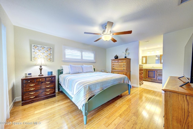 bedroom with ensuite bathroom, a textured ceiling, ceiling fan, and light hardwood / wood-style flooring