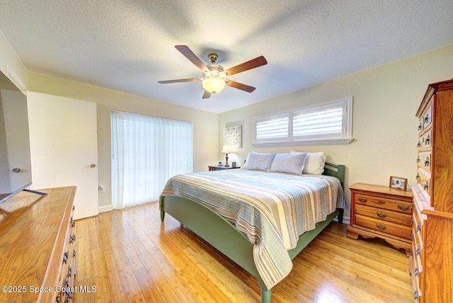 bedroom with light wood-type flooring, a textured ceiling, and ceiling fan