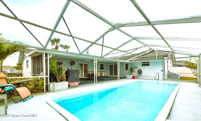 view of pool with french doors, a lanai, and a patio area