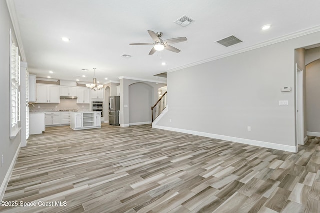 unfurnished living room with ceiling fan with notable chandelier, light hardwood / wood-style flooring, and ornamental molding