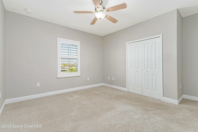 unfurnished bedroom featuring ceiling fan, a closet, and light carpet