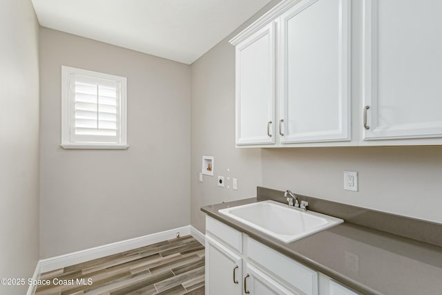 washroom featuring sink, electric dryer hookup, cabinets, washer hookup, and wood-type flooring