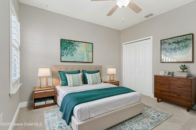 bedroom with light colored carpet, ceiling fan, and a closet