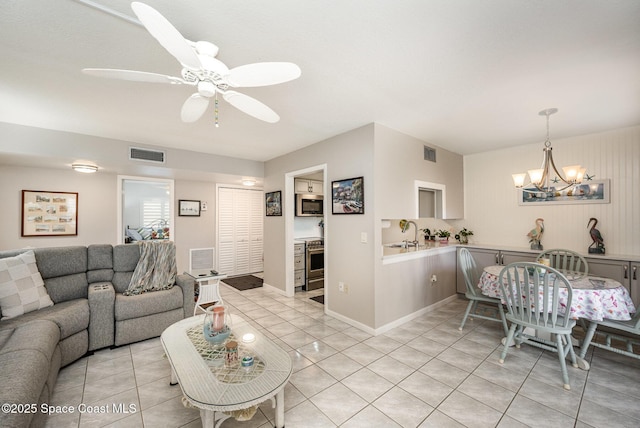 living room with light tile patterned floors, ceiling fan with notable chandelier, and sink