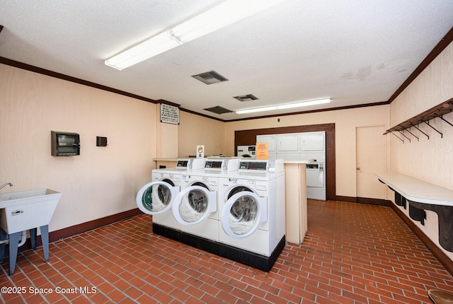 laundry room with washing machine and dryer, ornamental molding, and a textured ceiling