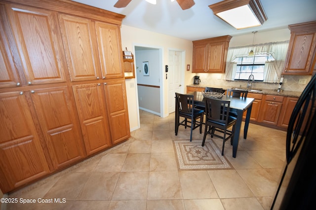 kitchen with black refrigerator, ceiling fan, backsplash, stone counters, and pendant lighting