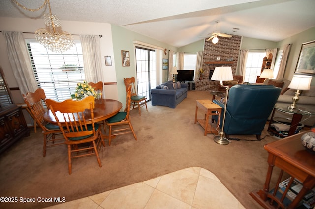 dining room featuring ceiling fan with notable chandelier, vaulted ceiling, light carpet, and a fireplace