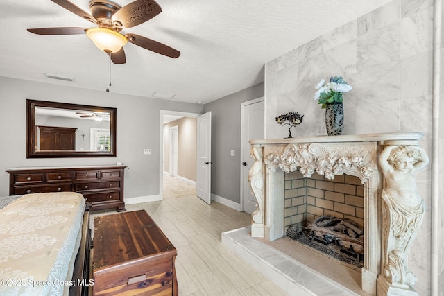 bedroom featuring ceiling fan, a premium fireplace, and a textured ceiling