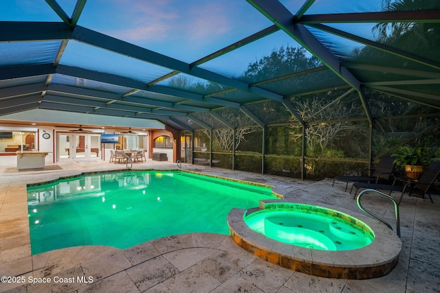 pool at dusk featuring an in ground hot tub, a lanai, ceiling fan, and a patio