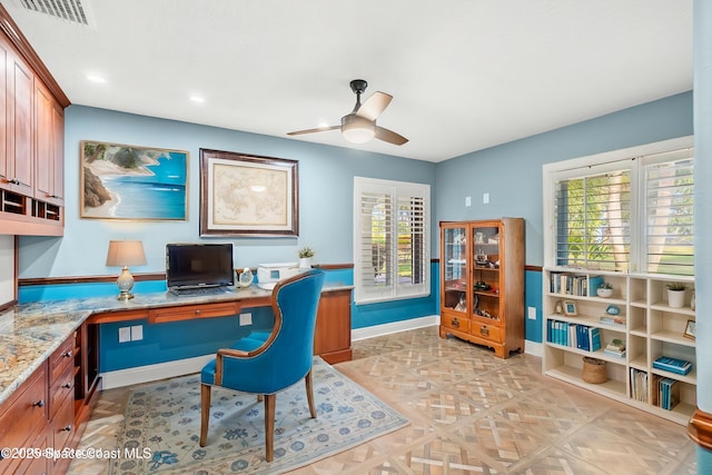 home office featuring ceiling fan, plenty of natural light, built in desk, and light parquet flooring