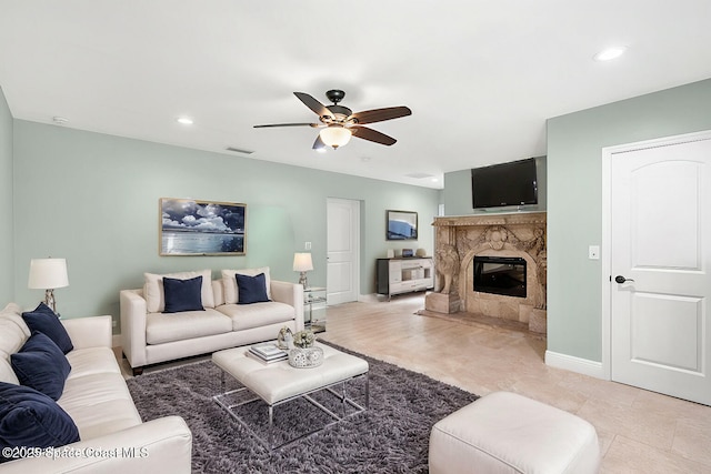 living room featuring a premium fireplace and ceiling fan