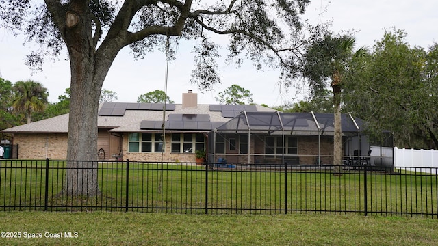 back of house featuring a lanai, solar panels, and a yard