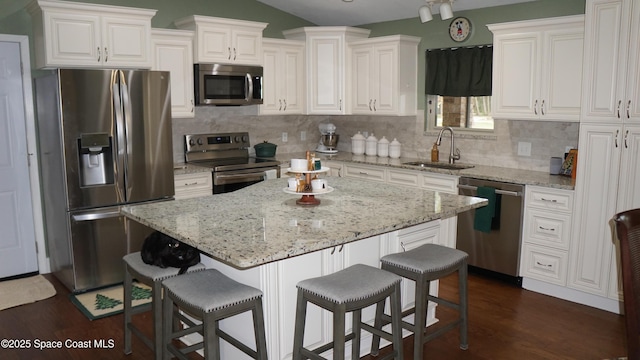 kitchen featuring white cabinets, appliances with stainless steel finishes, a center island, sink, and a breakfast bar