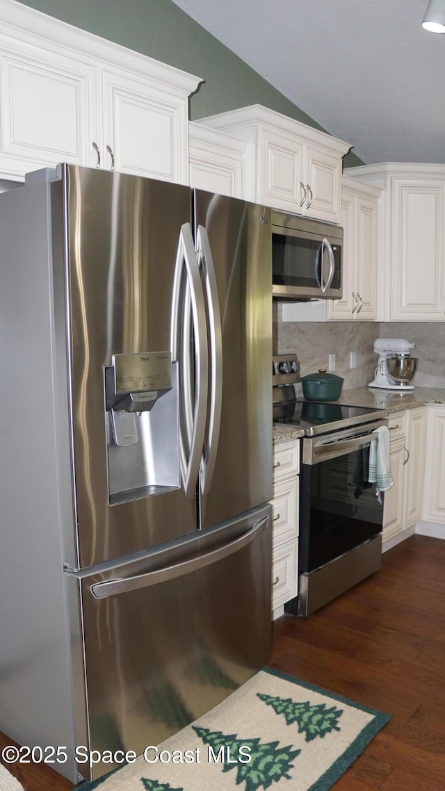 kitchen featuring stainless steel appliances, tasteful backsplash, dark wood-type flooring, vaulted ceiling, and white cabinets