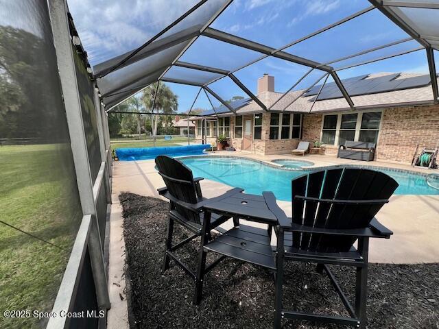 view of pool featuring an in ground hot tub, glass enclosure, and a patio