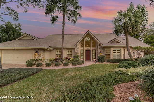 ranch-style home with a garage and a lawn