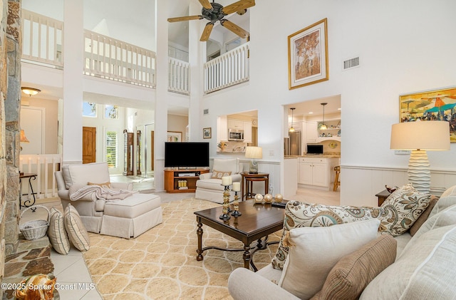 tiled living room with ceiling fan and a high ceiling