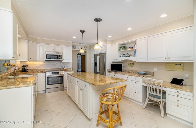 kitchen featuring appliances with stainless steel finishes, built in desk, white cabinetry, and a center island