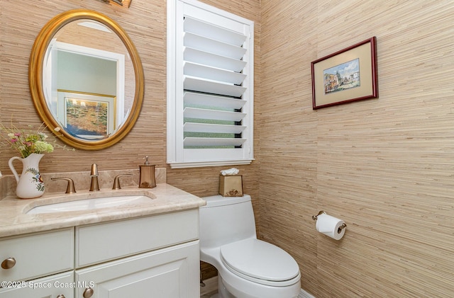 bathroom with toilet, wooden walls, and vanity