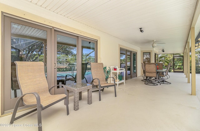 view of patio featuring ceiling fan and glass enclosure