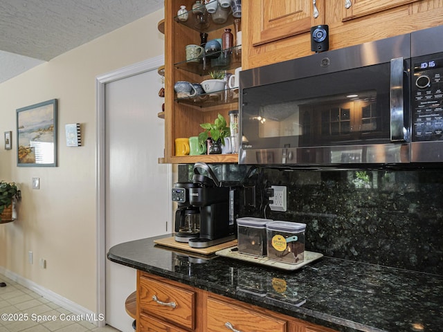 kitchen featuring light tile patterned floors, dark stone countertops, a textured ceiling, and decorative backsplash