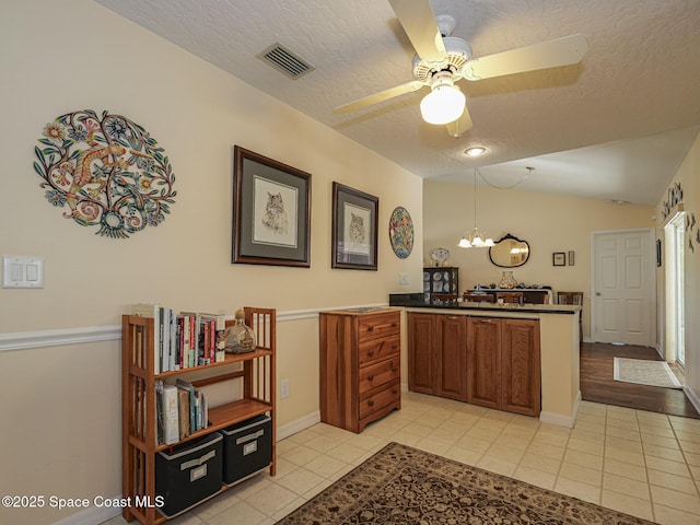 kitchen with light tile patterned floors, hanging light fixtures, a textured ceiling, vaulted ceiling, and kitchen peninsula