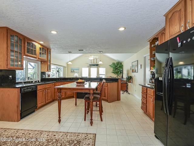 kitchen with lofted ceiling, decorative light fixtures, a textured ceiling, and black appliances