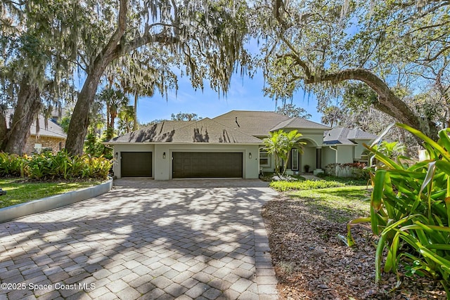 view of front of house featuring stucco siding, an attached garage, and decorative driveway