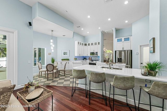 kitchen with a breakfast bar, a peninsula, stainless steel appliances, white cabinets, and glass insert cabinets