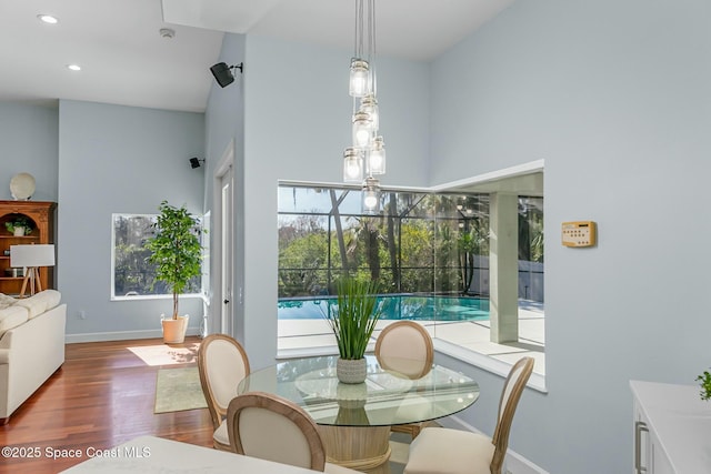 dining area with recessed lighting, baseboards, wood finished floors, and a sunroom