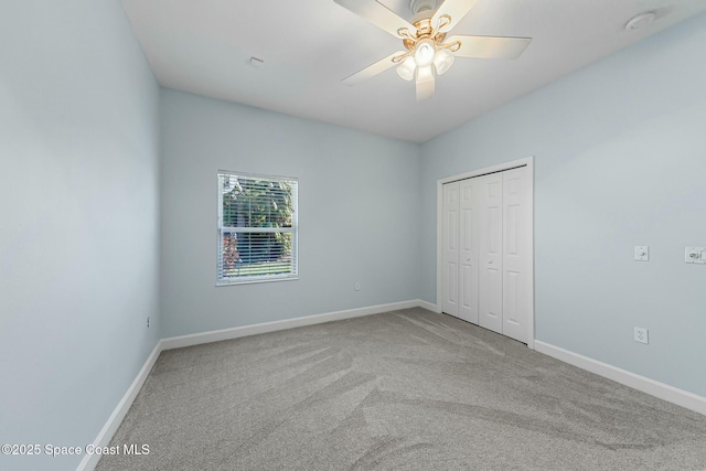 unfurnished bedroom with a closet, carpet flooring, ceiling fan, and baseboards