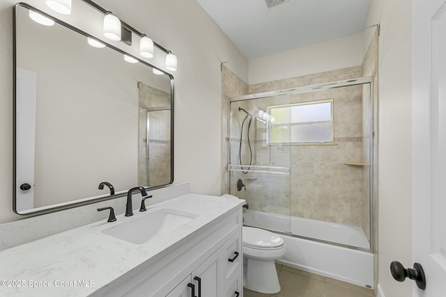 bathroom with vanity, visible vents, bath / shower combo with glass door, tile patterned floors, and toilet