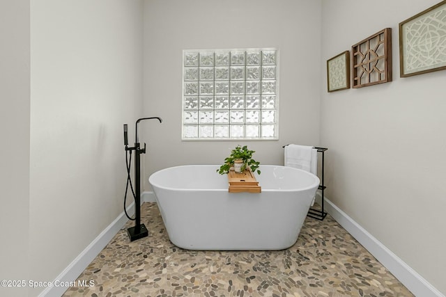 full bath featuring a freestanding tub and baseboards