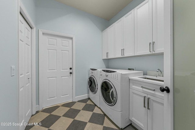 laundry room featuring a sink, baseboards, dark floors, cabinet space, and separate washer and dryer