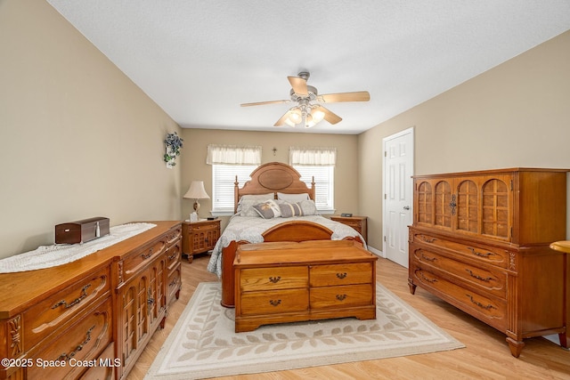 bedroom featuring ceiling fan, a textured ceiling, and light hardwood / wood-style flooring