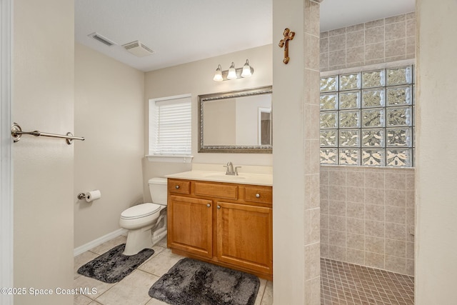 bathroom with toilet, a wealth of natural light, a tile shower, and vanity