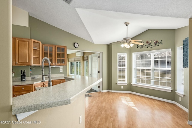 kitchen featuring a textured ceiling, lofted ceiling, light hardwood / wood-style floors, kitchen peninsula, and ceiling fan