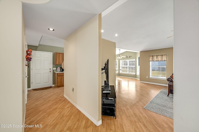 hallway featuring vaulted ceiling and light hardwood / wood-style floors